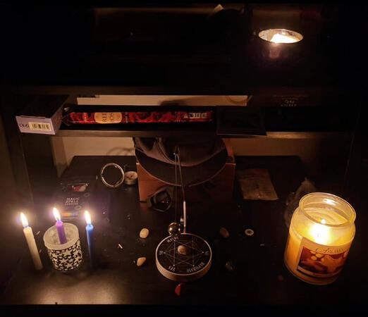 The board, candles, crystals, incense and cards that lay lit as Andonis speaks to the passed. The pink box, however, contains his Papa (grandfather), who passed away from Covid. The hat that lay on top is also his Papa's.